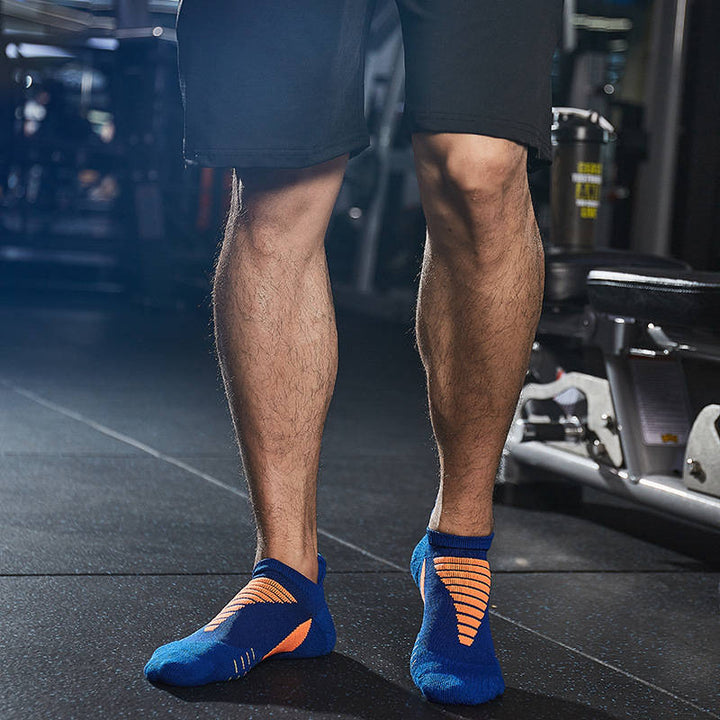 Athlete in a gym wearing blue and orange ankle sports socks.