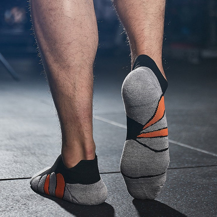 Man wearing black and gray ankle socks with orange accents in a gym setting.