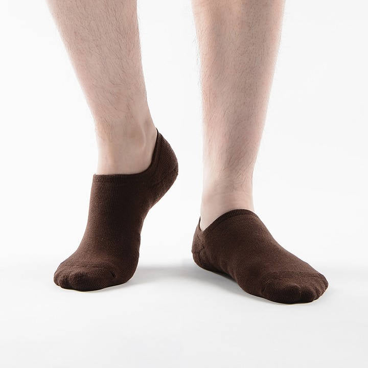 A pair of brown ankle socks on a person's feet against a white background.
