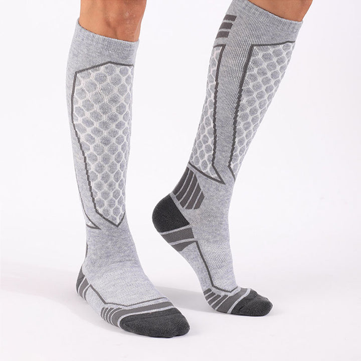 Person wearing grey thick padded merino wool over-the-calf skiing socks for warmth and support.