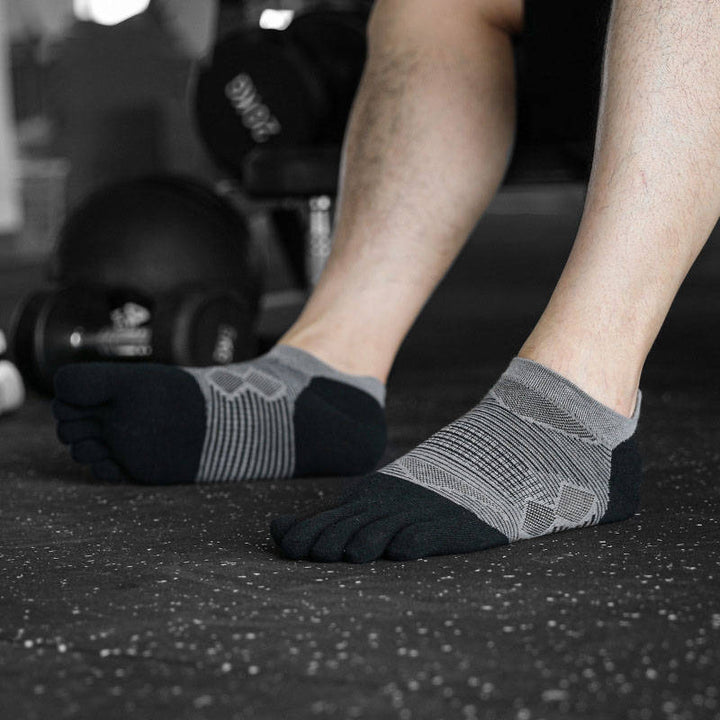 Person wearing grey and black toe socks in a gym environment.