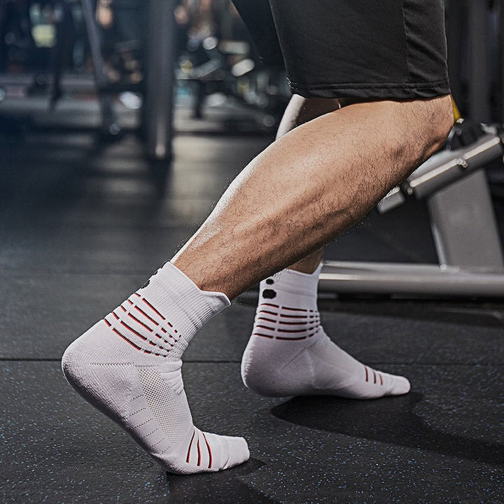 A person wearing white athletic socks with red accents, working out on gym equipment.